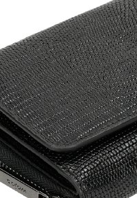 Zwart textuurportemonnee met een korrelig afwerking. Voorzien van een klep sluiting en zilveren hardware details. Compact ontwerp met een gladde binnenvoering.