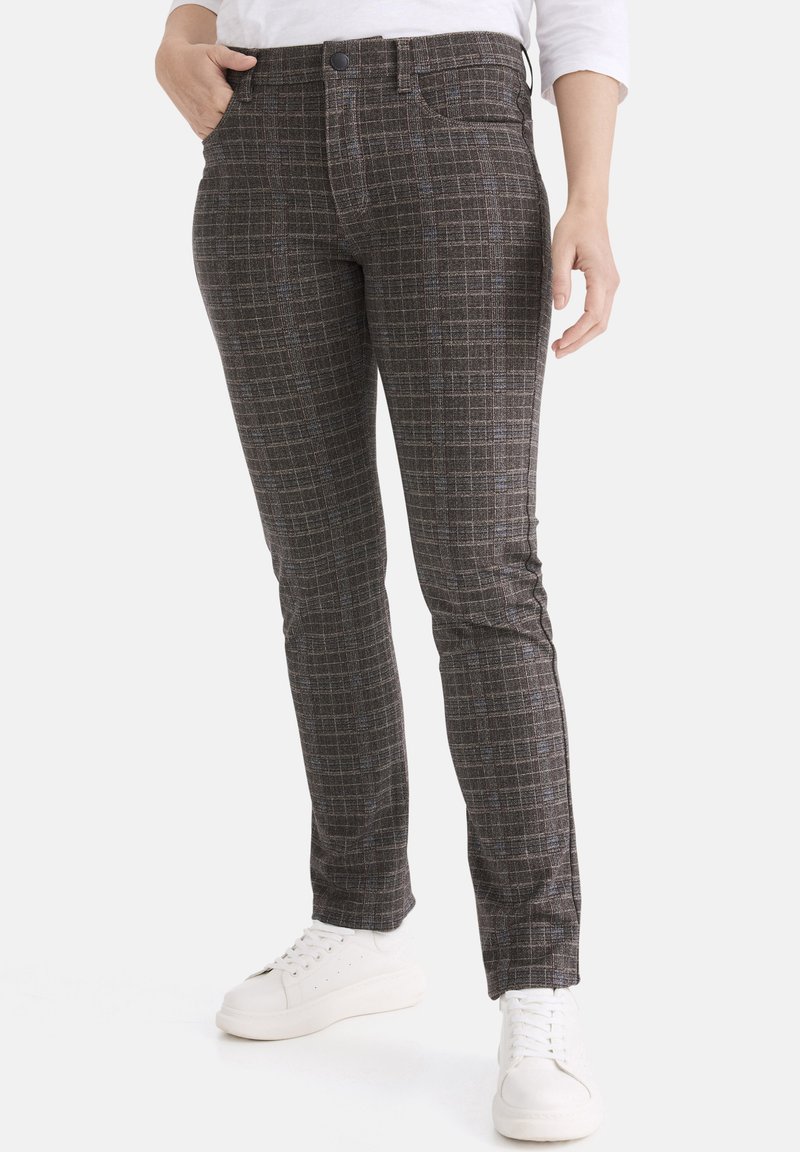 Karierte Stretchhose in Dunkelbraun mit blauen und orangefarbenen Akzenten. Besitzt ein tailliertes Design und Standardtaschen, kombiniert mit weißen Turnschuhen.