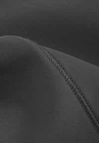 Tessuto elastico nero con una texture a coste, caratterizzato da una cucitura piatta lungo il bordo, adatto per capi di abbigliamento o applicazioni flessibili.