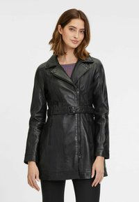 Zwarte leren jas met een taille met riem, ritssluiting en gedetailleerde stiknaad. Heeft een klassieke kraag en lange mouwen.