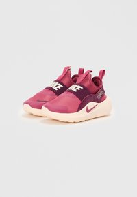 Lyserøde strækstof sneakers med en hvid Nike-logo rem, polstret krave og en struktureret sål. Designet har en afrundet tå og kontrasterende accenter.