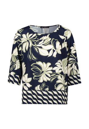 Marineblauwe bloemenblouse met korte mouwen, voorzien van witte en olijfgroene bloemmotieven en een golvende gestreepte zoom aan de onderkant. Gladde stofstructuur.