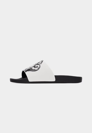 Juoda šlepetė su plačiu baltu diržu, puoštu juodu ornamentiniu raštu, rodoma ant paprasto šviesaus fono.