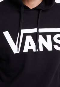 Felpa nera con cappuccio realizzata in tessuto morbido, con un audace logo bianco "VANS" sul petto e cordini neri sul cappuccio.