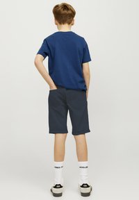 T-shirt en coton bleu marine, shorts bleu marine avec ourlets retroussés, chaussettes blanches et baskets noires. Design simple, sans motifs, style minimaliste.