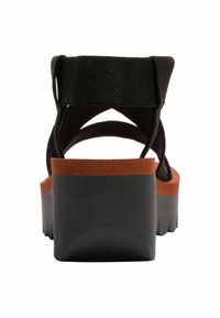 Černé sandály na pásky s tlustou černou platformou a hnědým akcentem kolem základny. Mají polstrované černé pásky pro pohodlí.