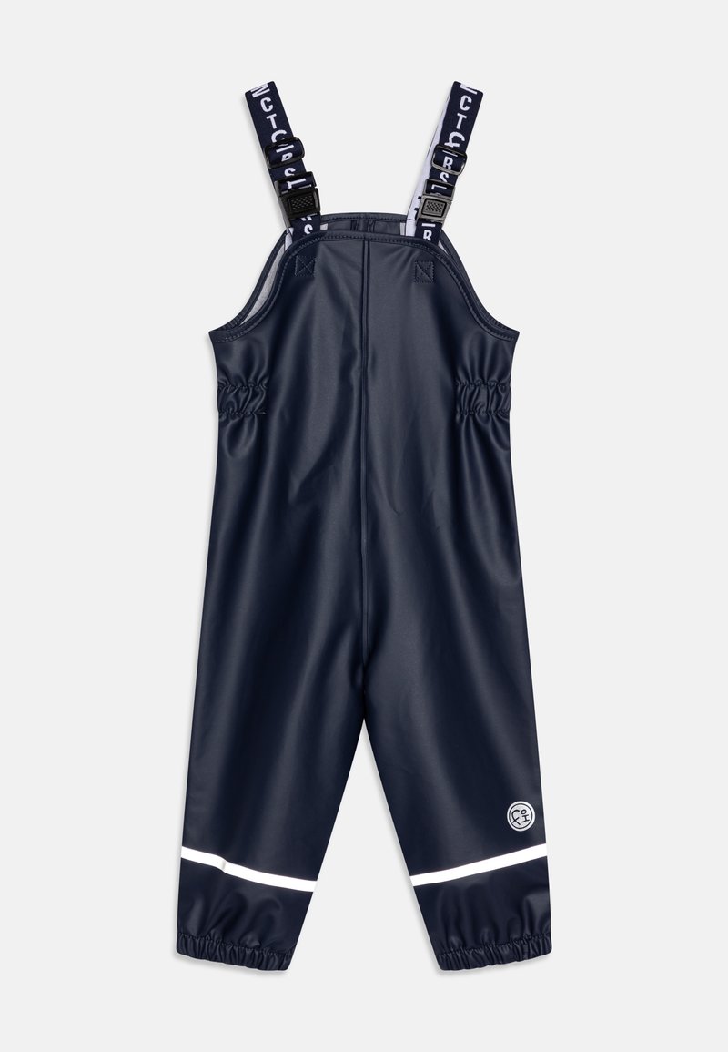 Salopette imperméable marine avec bretelles ajustables, taille élastiquée et bande réfléchissante blanche en bas. Texture lisse.