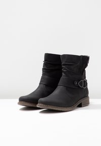 Botas negras hasta el tobillo hechas de material sintético, con una correa texturizada y una hebilla decorativa, tacón bajo apilado y diseño de parte superior fruncida.