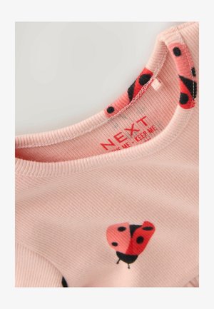 Ružičasta košulja od rebrastog materijala s okruglim izrezom. Ima grafiku bubamare u crvenoj i crnoj boji. Oznaka unutra kaže "NEXT."