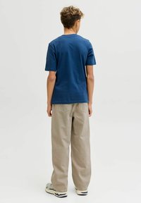 Camiseta de algodón de color azul marino con mangas cortas y cuello redondo, combinada con pantalones holgados de color beige claro. Calzado casual visible.