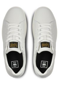 Baskets en cuir blanc avec des bouts ronds, lacets plats et un intérieur noir. Présente une languette texturée avec une étiquette logo à l'avant.