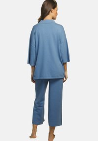 Ensemble de détente bleu avec un haut court à manches courtes et un pantalon court, fabriqué en tissu doux avec une finition texturée.