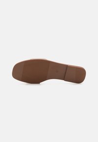 Brun gummisåle med flat design, som har en glatt finish og horisontale riller for grep. Rund tåform med minimale detaljer.