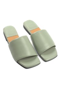 Grüne Kunstleder-Sandalen zum Hineinschlüpfen mit einem breiten Riemen, quadratischer Zehenpartie und einer gepolsterten, hellbraunen Innensohle. Die Sohle ist schwarz und flach.