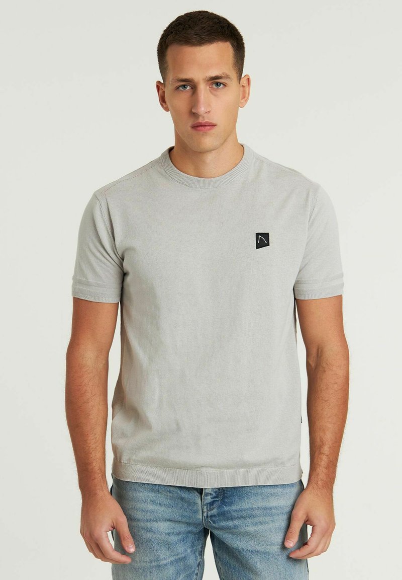 Lichtgrijze T-shirt met korte mouwen van zacht materiaal, met een ronde halslijn en een klein zwart logopatch op de borst.