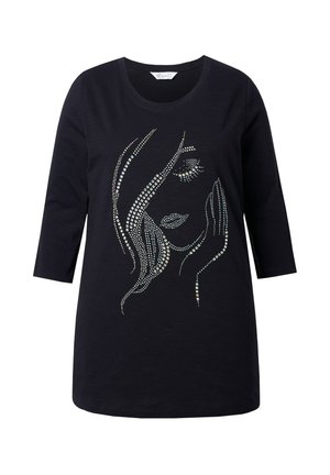 Camisa negra de manga larga con un diseño de strass de la cara de una mujer con los ojos cerrados y la mano descansando en su mejilla.