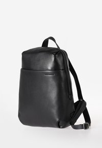 Zaino in pelle nera con finitura testurizzata, dotato di chiusura superiore con zip, spallacci regolabili e design minimalista.