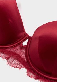 Rød satin-bh med blonder, der har polstrede skåle, justerbare stropper og en dekorativ nøglehulldetalje i midten.