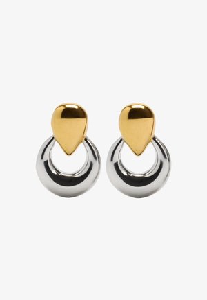 Kolczyki z metalu złotego i srebrnego mają kształt łezki u góry, połączone z okrągłym kółkiem, z połyskującą, refleksyjną powierzchnią.