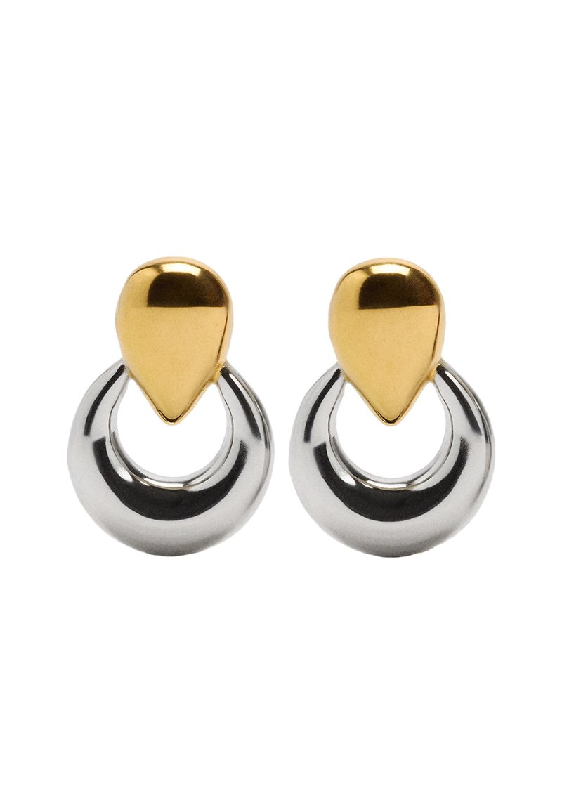 Kolczyki z metalu złotego i srebrnego mają kształt łezki u góry, połączone z okrągłym kółkiem, z połyskującą, refleksyjną powierzchnią.
