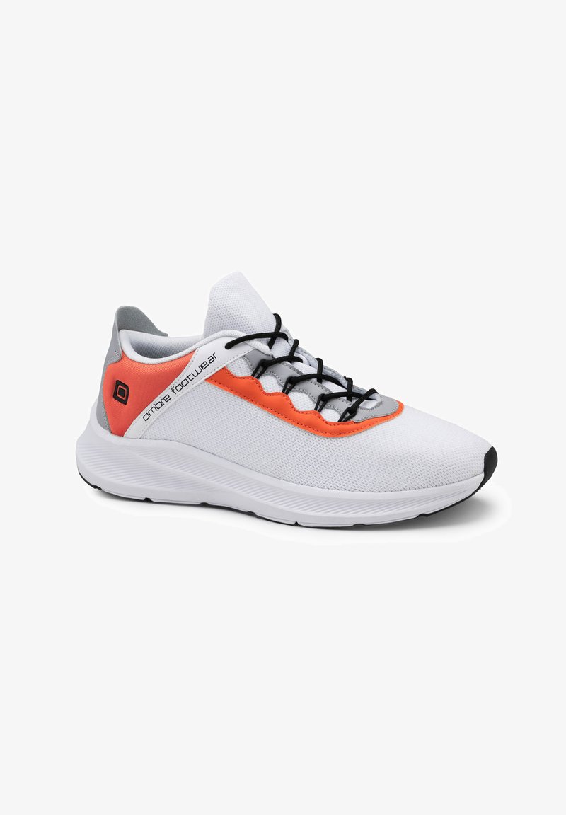 Chaussure de sport blanche avec une tige en maille, des accents orange sur les côtés, des lacets noirs et une semelle en caoutchouc noir avec une surface texturée.