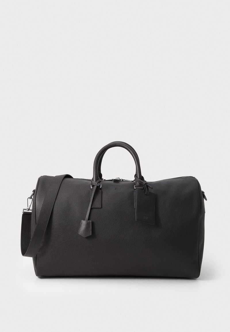 Black leather duffel bag with rounded handles, adjustable shoulder strap, zipper closure, and a small rectangular luggage tag. Smooth texture.