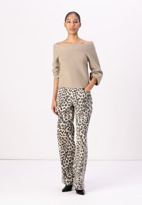 Beige off-the-shoulder ribbed sweater paired with wide-leg, patterned pants featuring a black and beige leopard print. Black heels complete the look.