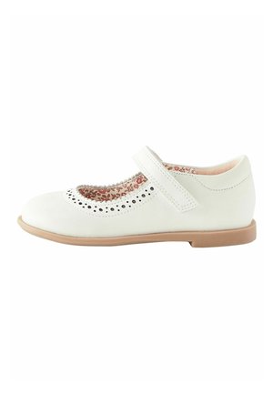 Hvid Mary Jane-sko til børn med perforerede detaljer, blomsterindvendig foring, velcrorem og lys brun flad sål, sideudsigt.