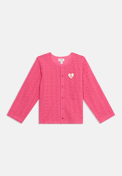 Haut rose à manches longues boutonné avec un motif en zigzag et un patch en forme de cœur sur la poitrine gauche indiquant "BLAH BLAH BLAH."