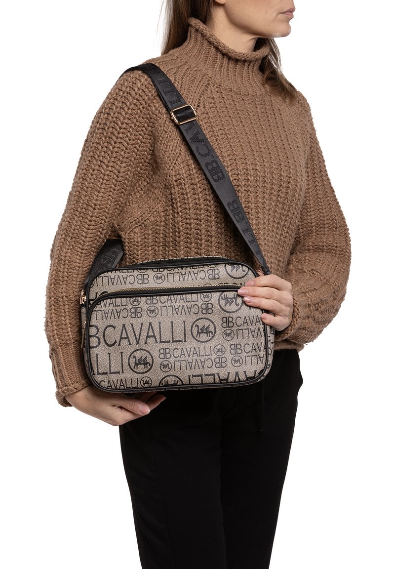 Borsa a spalla beige con motivo testuale ripetuto "Cavalli". Presenta una tracolla nera e chiusura con cerniera. Forma rettangolare con una texture liscia.