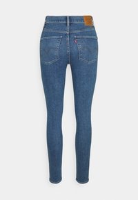 Vaqueros skinny en denim azul oscuro. Cuenta con dos bolsillos traseros con costura curva y una etiqueta de cuero de marca en la cintura. Acabado limpio.