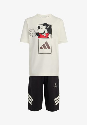 Chemise blanche à manches courtes avec graphique Mickey Mouse et short noir avec le logo Adidas et des bandes blanches sur les côtés.
