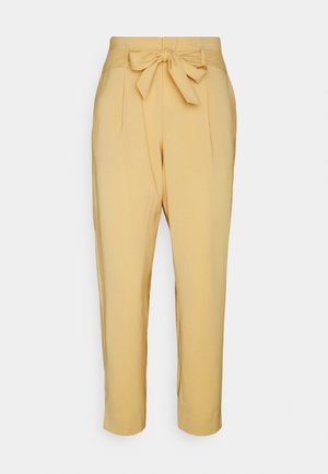 Beżowe spodnie z wysokim stanem, zwężane, z zakładkami i materiałowym paskiem zawiązanym na kokardę w talii, długość do kostek.