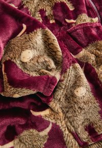 Plush blanket featuring a burgundy background with a brown, textured animal pattern. Soft, fuzzy material with a deep pile.