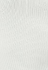Tessuto bianco a costine con una consistenza delicata, caratterizzato da righe verticali, superficie liscia e un motivo uniforme in tutto il tessuto.