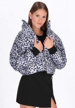 Leopard print puffer jacket in gray and black, featuring a cropped design, zip front, and ribbed cuffs. Worn over a black top and skirt.