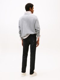 Grijze sweatshirt met hoge kraag, zwarte jeans en lichte sneakers. Focus op casual pasvorm en gestructureerde stof. Eenvoudig ontwerp, neutrale kleuren.