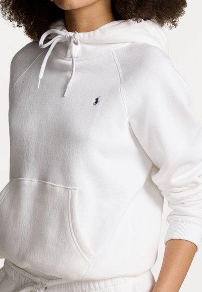 White hoodie made of soft fabric with a kangaroo pocket, drawstring hood, and a small blue logo on the chest. Ribbed cuffs and hem.