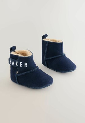 Otroški škornji temno modre barve iz semiša z umetnim krznom v notranjosti. Imajo bočni trak z napisom "BAKER" in dekorativno šivanje. Mehka podplatna zasnova.