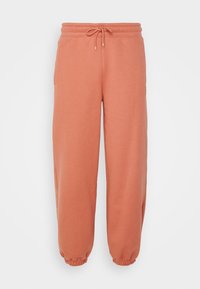 Perzikkleurige sweats met een zachte stof, voorzien van een elastische tailleband met een trekkoord, zijzakken en elastische manchetten bij de enkels.
