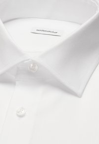 Hvid skjortekrave med to klare knapper og et mærke med teksten "seidensticker" indeni kraven.