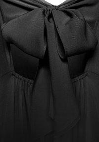 Juoda suknelė su dideliu kaspino akcentu iškirpėje, pagaminta iš lygaus, plaukioto audinio su surinkta juosmens dalimi ir švelnia tekstūra.