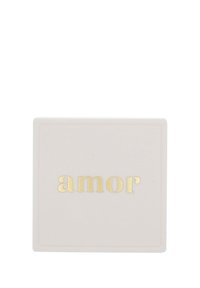 Vitt fyrkantigt objekt med guldpräglade ordet "amor" centrerat på ytan.