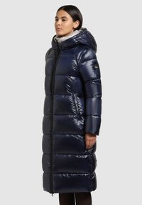 Hosszú tengerészkék puffertakaró fényes felülettel, kapucnival, vízszintes steppelt részekkel, fekete cipzárral és oldalzsebekkel.