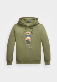 Sudadera verde de algodón con un gráfico de un oso con gafas de sol y camiseta, con cordones y puños acanalados. Logo en la parte inferior.