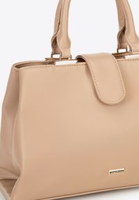 Sac à main en cuir beige avec une forme structurée, deux poignées courtes, fermeture magnétique et un accent logo doré à l'avant. Texture lisse.