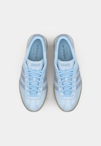 Svijetloplave nubuk tenisice s tri bijele pruge i odgovarajućim vezicama. Imaju teksturiranu prednju stranu i gumeni potplat. Logo se nalazi na jeziku i unutar obuće.