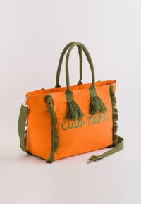 Bolsa de lona naranja con flecos verdes, doble asa y una correa ajustable. Presenta "ciao mare" bordado en verde.