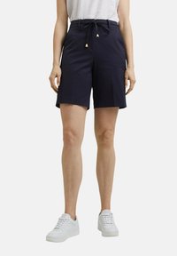 Pantalones cortos azul marino de tejido ligero con cintura ajustable por cordón, presentan puntas en tono dorado y un diseño a medida.