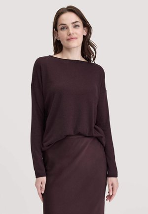Burgunderfarbener Pullover mit langen Ärmeln und weitem Ausschnitt, kombiniert mit einem passenden knielangen Rock aus einem glatten Stoff mit minimaler Textur.